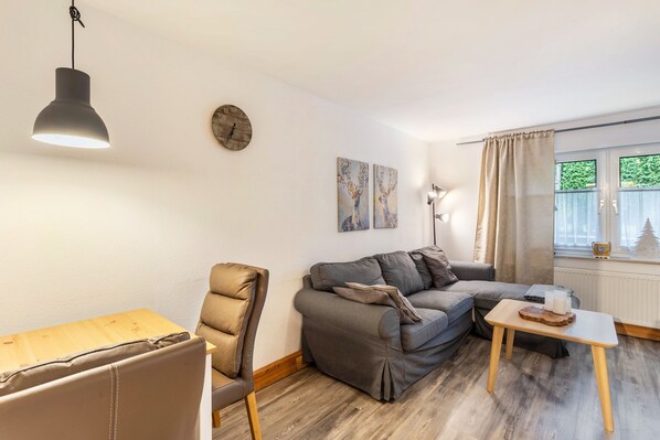 Una sala de estar moderna con un sofá, una silla, una mesa de madera y una lámpara colgante.