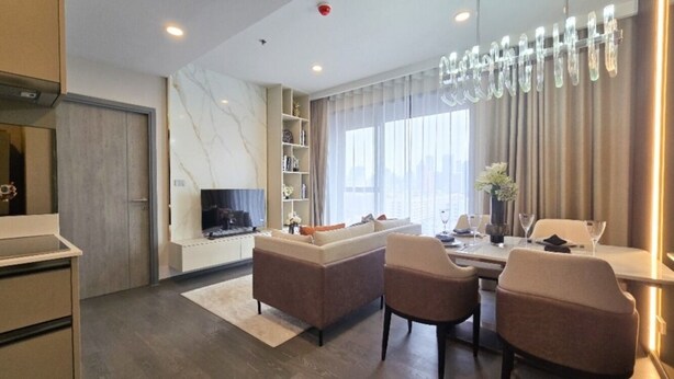 A modern living room with a sofa, chairs, a TV, and a dining area with a table and chairs.