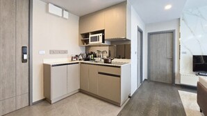 A modern kitchen with built-in appliances, a microwave, and a sink. There is a door leading to another room and a marble countertop.
