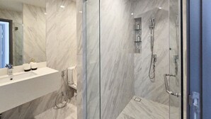 A modern bathroom with a marble vanity, a glass shower enclosure, and a large mirror.
