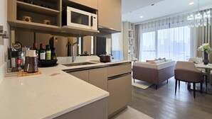 A modern kitchen with a microwave, stove, and various kitchen items. There is a dining area with a table and chairs, and a sofa.