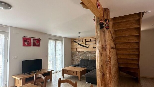 Ein gemütliches Wohnzimmer mit einem Holzesstisch, einer Couch und einem Fernseher.