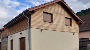 Ein zweistöckiges Gebäude mit geneigtem Dach, Holzverkleidung und zwei Fensterläden.