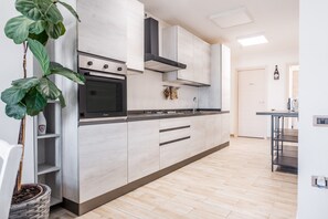 Una cocina moderna con horno integrado, armarios de acero inoxidable y una gran planta en maceta.