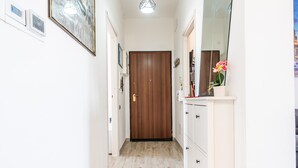 A hallway with a wooden door, white cabinets, and a mirror.