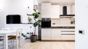 A modern kitchen with a dining area, a flat-screen TV, and a clock on the wall.