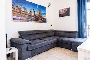 Una sala moderna con un sofá seccional, una pintura de un paisaje urbano y una obra de arte de 'JOKER'.