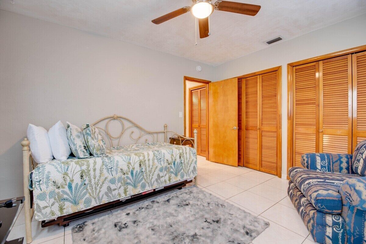 A bedroom with a bed, a ceiling fan, and wooden closets.