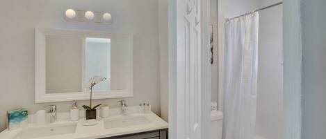 Un baño con lavamanos doble, inodoro y zona de ducha.