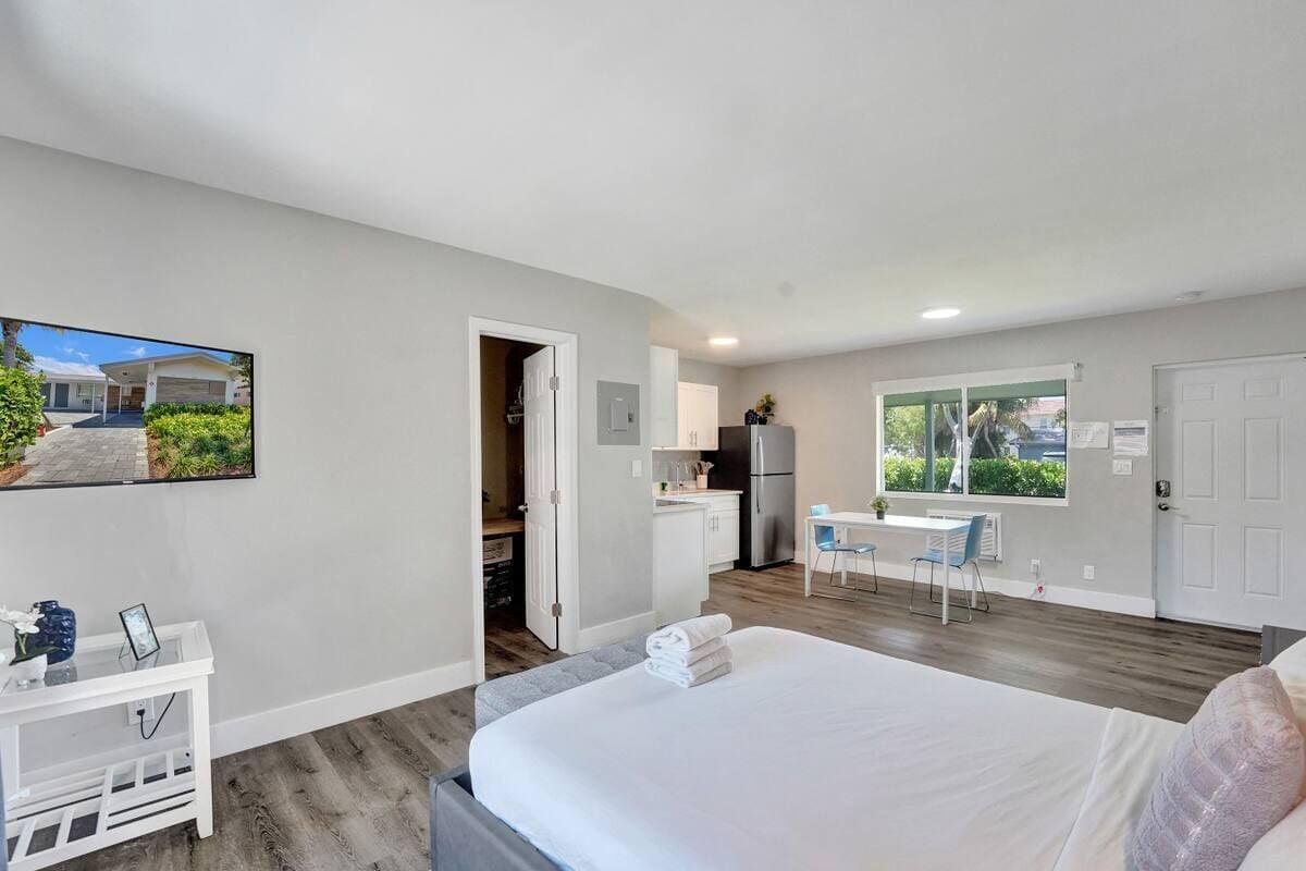 Une chambre d’hôtel moderne dotée d’un grand lit, d’un petit bureau, d’une kitchenette et d’une fenêtre donnant sur l’extérieur.