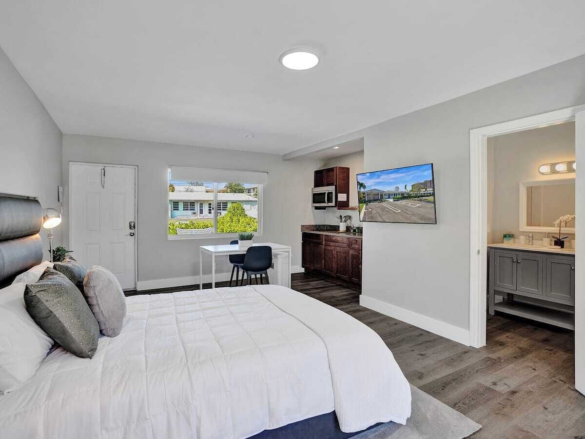 A bedroom with a large bed, a desk, and a view of the outside.