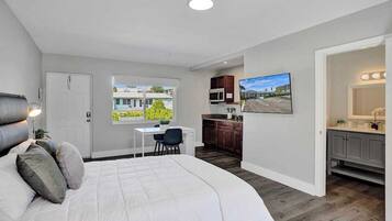 A bedroom with a large bed, a desk, and a view of the outside.