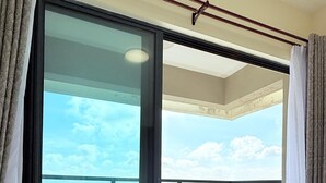 Habitación de hotel en un edificio alto con un balcón grande y vistas a la ciudad.