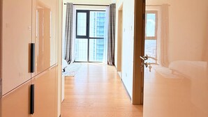 Pasillo de hotel con suelo de madera, un amplio cristalero corredizo que da a un balcón y un baño con bañera.