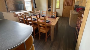Una cocina compacta con armarios de madera, una mesa de comedor para cuatro personas y un refrigerador pequeño.