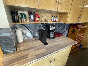 Una cocina con cafetera, toallas de papel y diversos alimentos en la encimera.