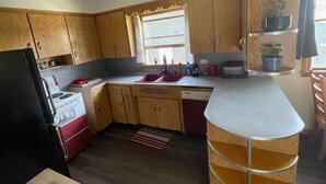 Una cocina compacta con armarios de madera, estufa, pileta y una encimera.