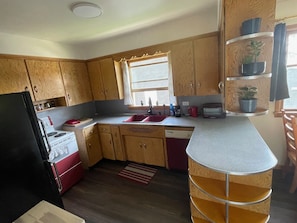 A compact kitchen with wooden cabinets, a stove, a sink, and a countertop.