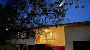Una casa con cerca blanca, una escalera y un árbol en primer plano.