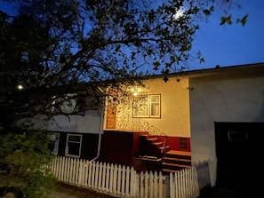 A house with a white fence, a staircase, and a tree in the foreground.