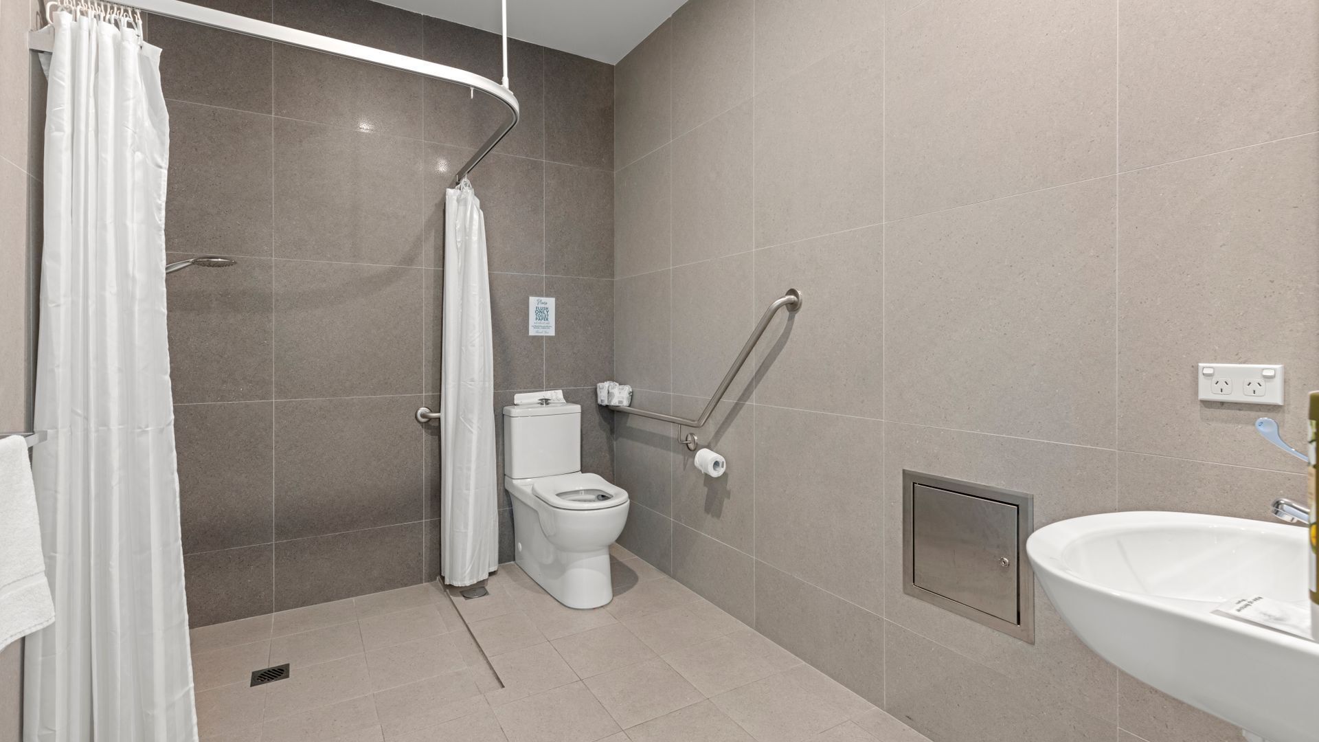 A modern bathroom with a shower, toilet, and sink.