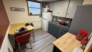 A compact kitchen with a dining table, chairs, a refrigerator, a sink, and a coffee maker. - Welcome to the Cabernet Escape– A Bold, Wine-Inspired Urban Escape (Calgary)