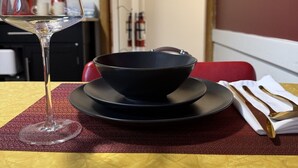 A dining table with a wine glass, a black bowl, and a napkin on a textured tablecloth. - Welcome to the Cabernet Escape– A Bold, Wine-Inspired Urban Escape (Calgary)