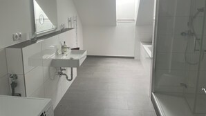 Un baño moderno con tragaluz, ducha y tocador con espejo.