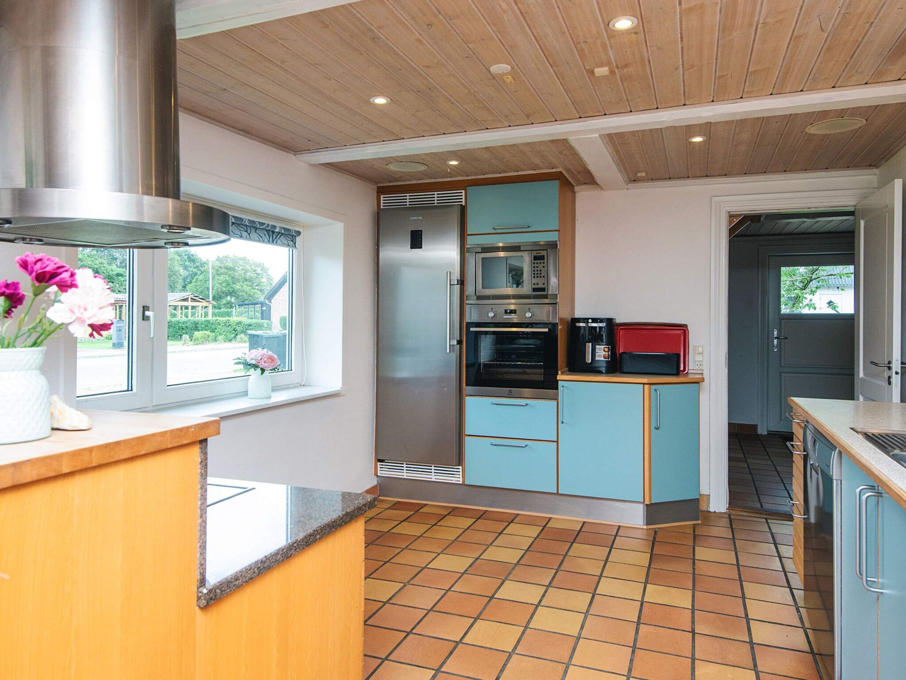 A kitchen with a stainless steel range hood, a microwave, an oven, and a coffee maker on the countertop.