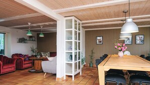 A spacious living area with a wooden dining table, red sofa, and a white cabinet. - 4 Star Holiday Home in Henne (Henne)