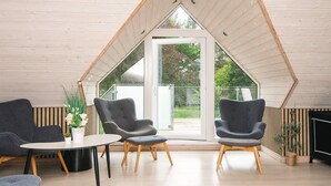 A modern interior with a sloped ceiling, two grey armchairs, a small table, and a potted plant. - 4 Star Holiday Home in Henne (Henne)
