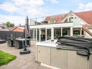 A backyard with a hot tub, outdoor furniture, and a covered patio area. - 4 Star Holiday Home in Henne (Henne)
