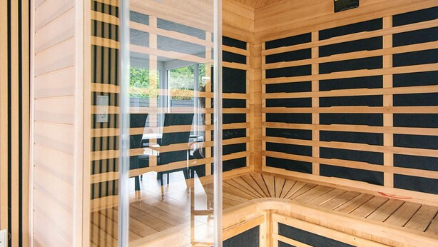 A sauna with a wooden interior, glass walls, and a bench. - 4 Star Holiday Home in Henne (Henne)