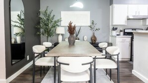 A modern kitchen with white cabinets, a built-in stove, and a dining area with a long table and white chairs. - Cozy 3b2b Duplex Home in South Austin (Austin)
