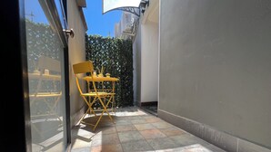 A narrow outdoor space with a yellow folding chair and a small table, a tiled floor, and a glass door leading to a balcony. - [ Duomo Delight ] + Self Check-in Late (Catania)