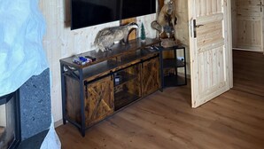 A wooden interior with a mounted TV, a wooden cabinet, and a door leading to another room. - Chalet on the Wolfsberg (Harzgerode)