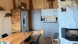 A rustic kitchen with wooden walls, a stone fireplace, and a dining area with a wooden table and chairs. - Chalet on the Wolfsberg (Harzgerode)