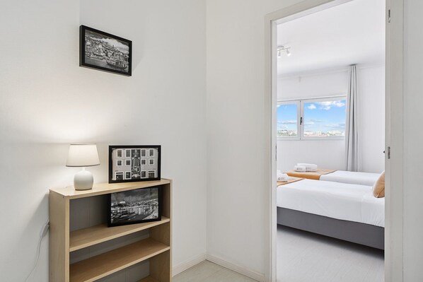 A modern hotel room with a bed, a bedside table with a lamp, and a framed picture on the wall.