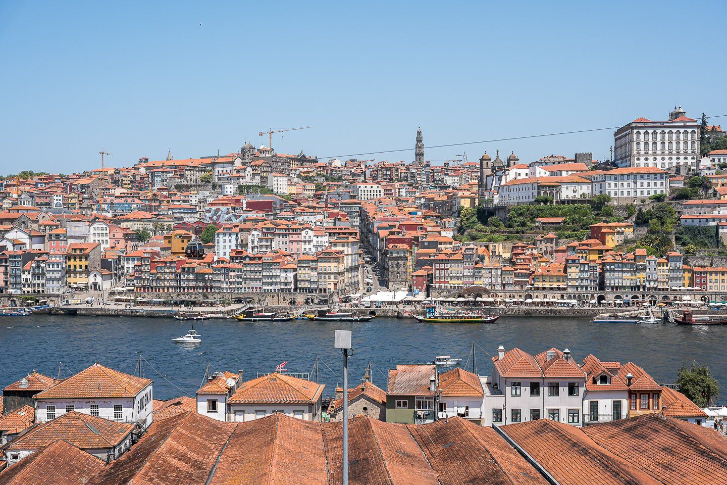 A coastal cityscape with historic buildings, a river, and a prominent tower.