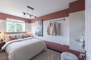 Une chambre à coucher comprenant un lit, une table de chevet, une étagère fixée au mur et une fenêtre donnant sur un paysage verdoyant.
