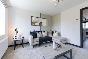 Un salon moderne comprenant un canapé, une table basse, une table d’appoint, un miroir et un radiateur.