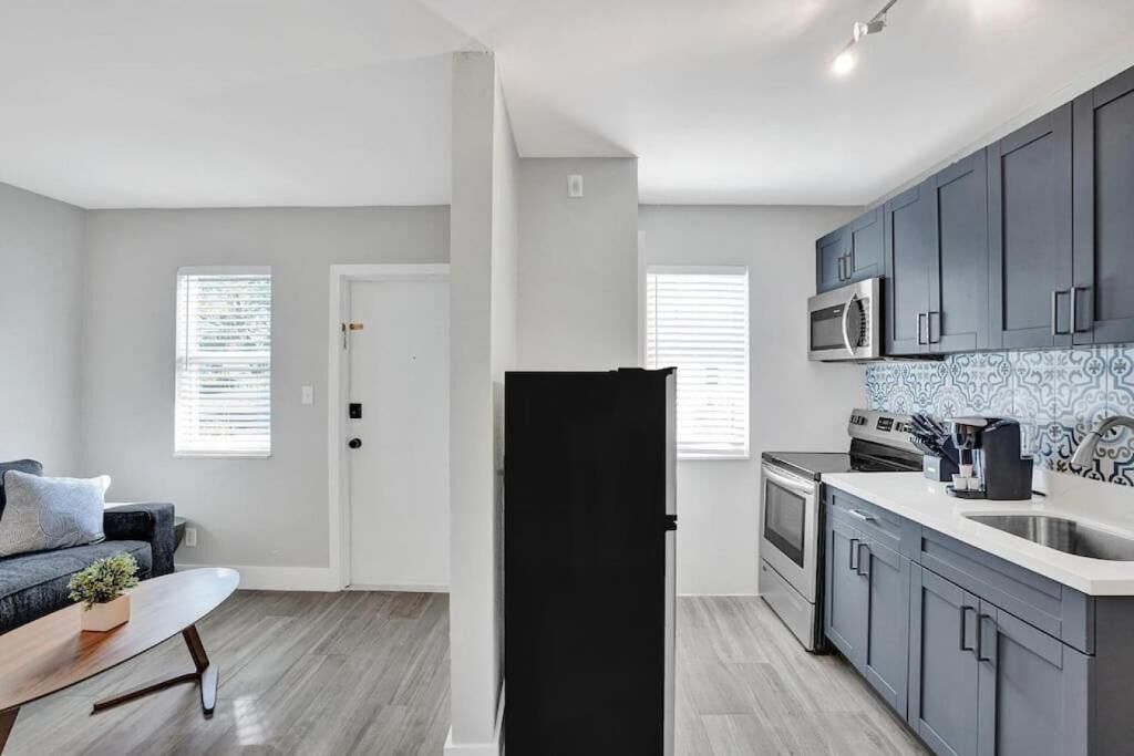 A modern kitchen with grey cabinets, a stainless steel microwave, and a coffee maker.