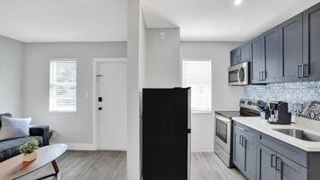 A modern kitchen with grey cabinets, a stainless steel microwave, and a coffee maker.