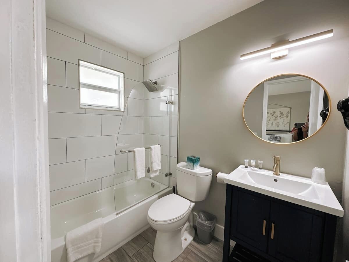 Un baño moderno con ducha envuelta en cristal, inodoro blanco, tocador con lavabo y espejo.
