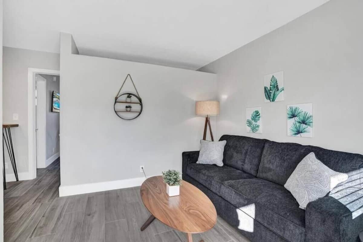 Ein modernes Wohnzimmer mit grauem Sofa, einem Holztisch und Wandbildern.