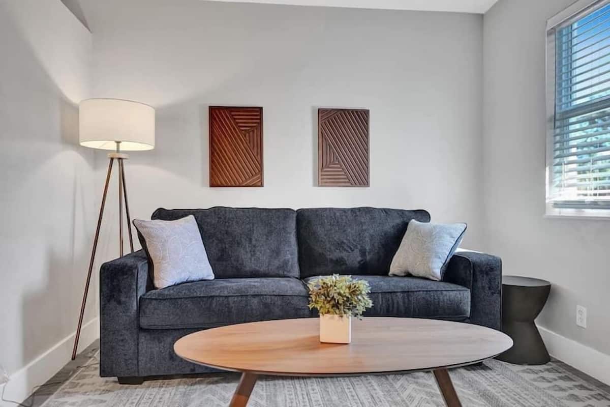 Ein modernes Wohnzimmer mit einem grauen Sofa, einem runden Couchtisch und zwei Wandbildern.