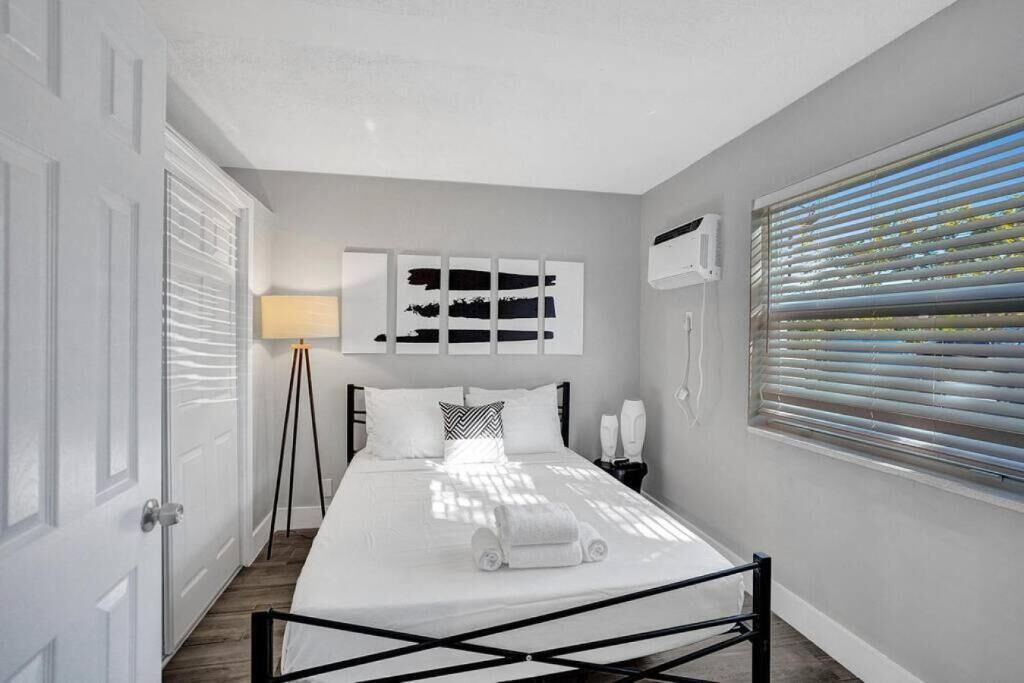 A modern bedroom with a bed, bedside table, lamp, and artwork on the wall.