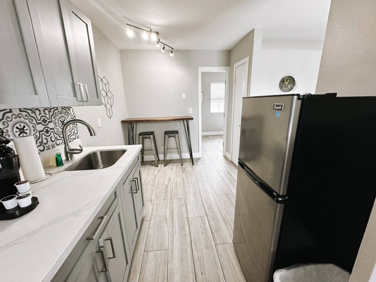 A modern kitchen with a stainless steel refrigerator, a countertop with a coffee maker, and a tiled backsplash.