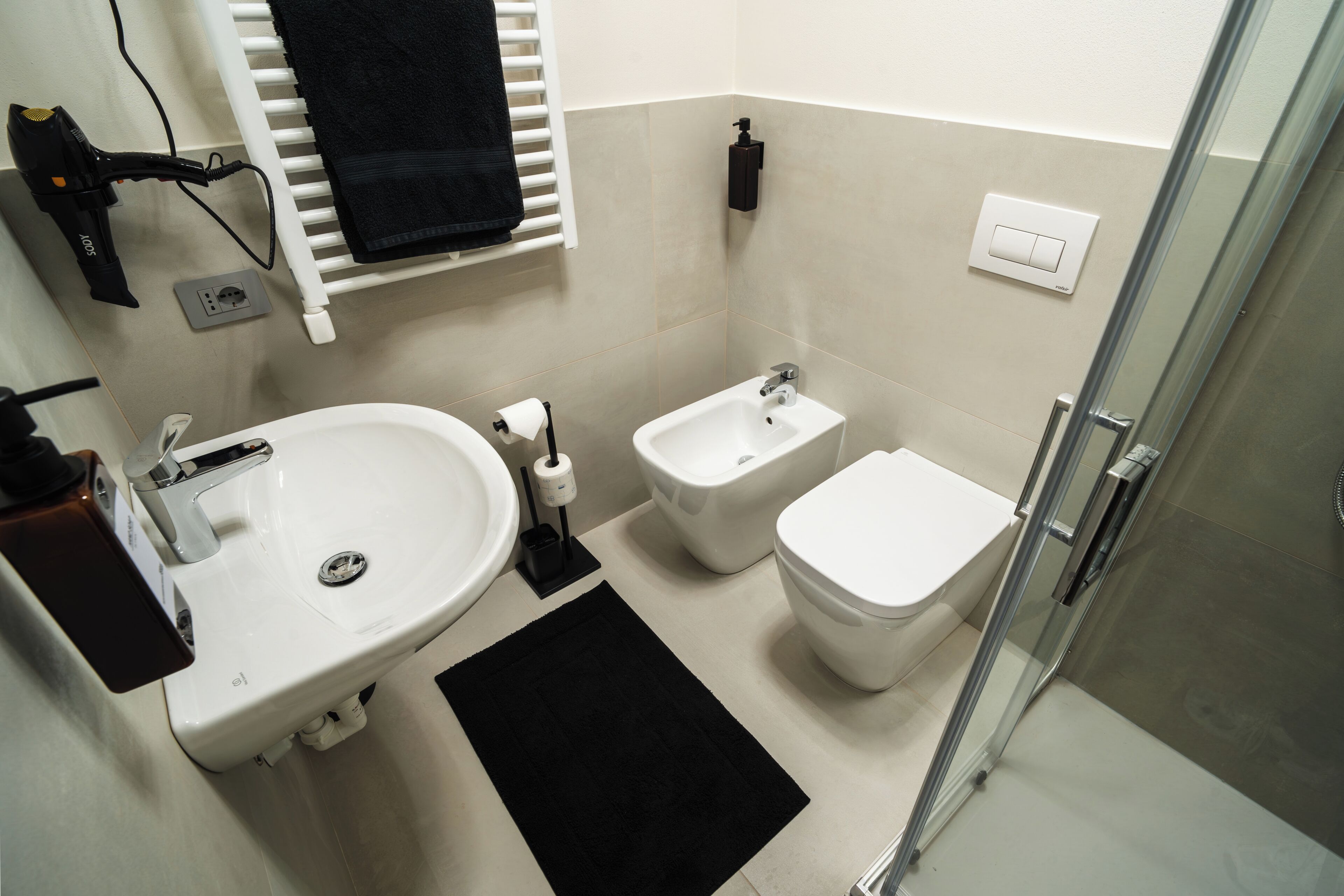 Un bagno con lavandino, bidet, wc e cabina doccia in vetro.