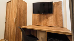 A room with a wooden wardrobe, a desk with a chair, and a mounted television. - Elysium Self Check-In Rooms (Trezzo sull'Adda)